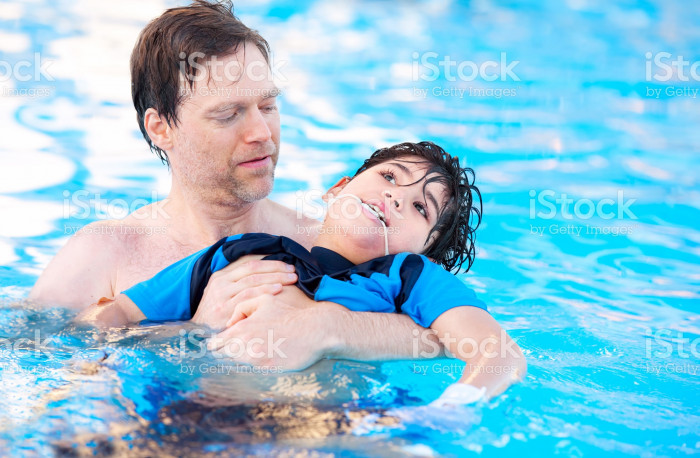 483393942-father-swimming-in-pool-with-disabled-child